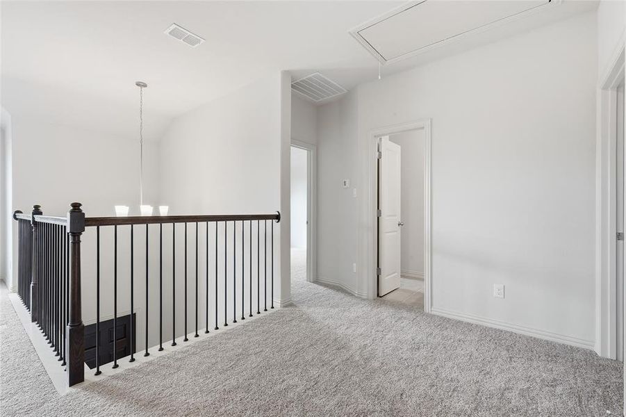 Corridor featuring attic access, carpet floors, and a chandelier Corridor featuring attic access, carpet floors, and a chandelier