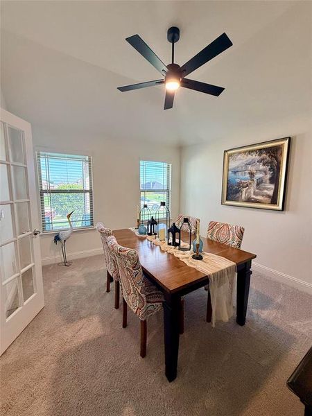 Dining area featuring a contemporary ceiling fan with integrated lighting, twin windows with horizontal blinds, and neutral carpeting Dining area featuring a contemporary ceiling fan with integrated lighting, twin windows with horizontal blinds, and neutral carpeting