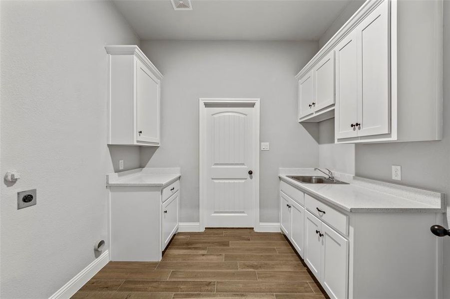 Laundry area with electric dryer hookup, sink, and cabinets