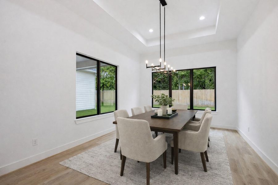 Walls of windows bring in natural light and views of the backyard, while a modern chandelier and tray ceiling add depth and sophistication to this versatile dining space. *Virtually Staged* Walls of windows bring in natural light and views of the backyard, while a modern chandelier and tray ceiling add depth and sophistication to this versatile dining space. *Virtually Staged*