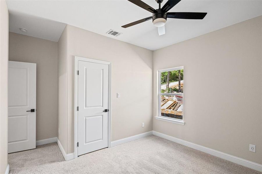 Neutral-toned room with plush carpet flooring and a ceiling fan with light fixture