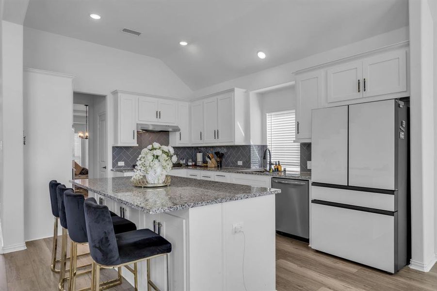 Kitchen with light hardwood / wood-style floors, high end white fridge, a kitchen island, dishwasher, and white cabinets