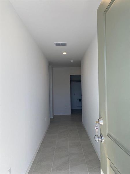 Hallway featuring light tile patterned floors, visible vents, and baseboards