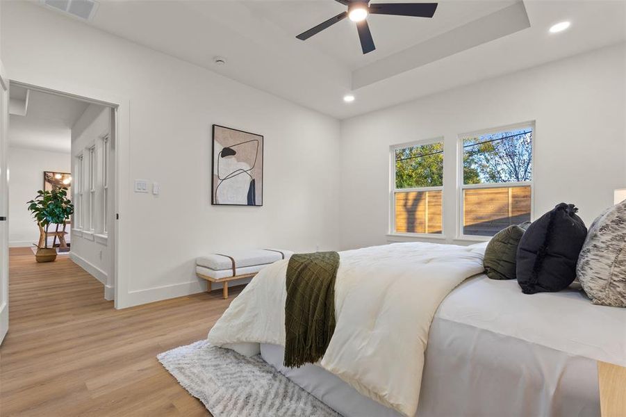 Bedroom with light wood-type flooring, recessed lighting, a tray ceiling, and ceiling fan