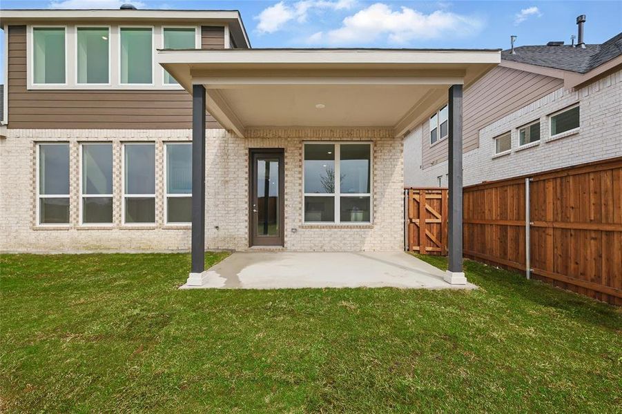 Back of house with brick siding, fence, a yard, and a patio area