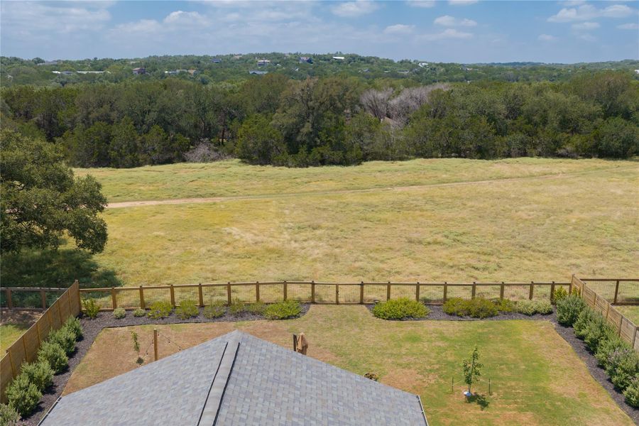 Overlooking expansive natural landscape, a well-maintained yard features a durable shingle roof.