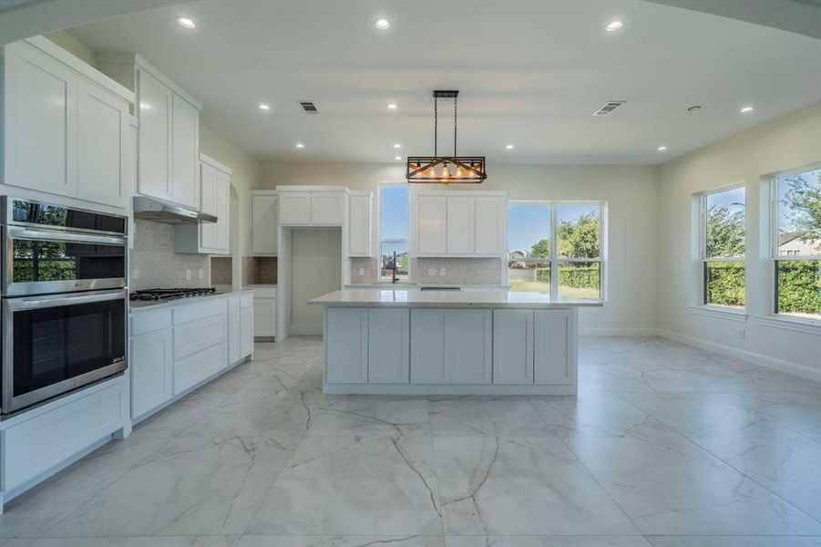 Kitchen featuring light marble finish floors, white cabinetry, decorative backsplash, pendant lighting, and recessed lighting Kitchen featuring light marble finish floors, white cabinetry, decorative backsplash, pendant lighting, and recessed lighting