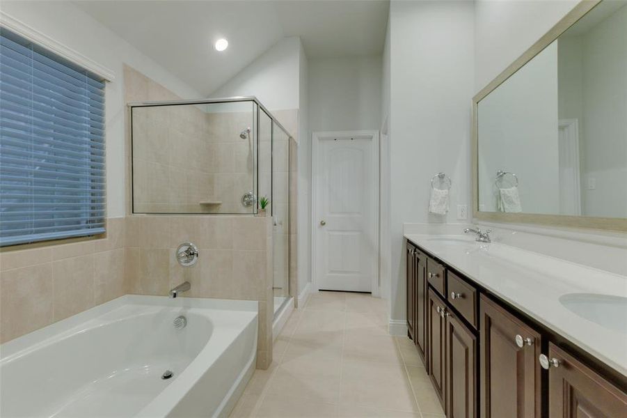 Bathroom featuring vanity, tile patterned flooring, and plus walk in shower