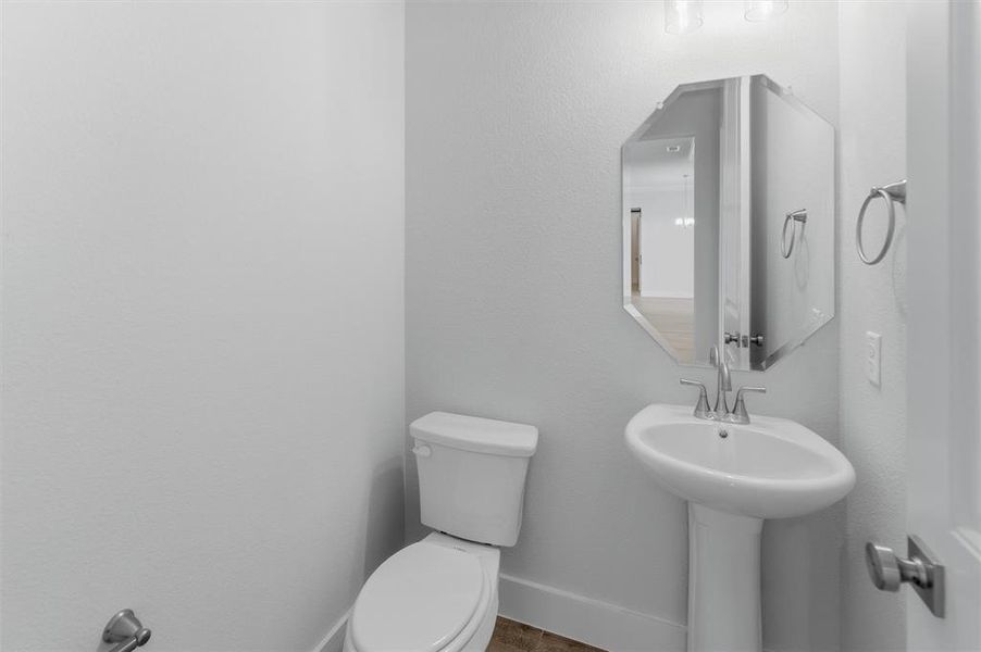 Pedestal sink with chrome faucet, octagonal mirror, and wall-mounted light fixture