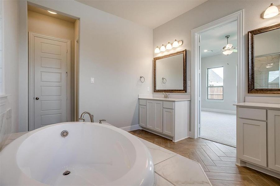 Bathroom featuring parquet floors, a bath, vanity, and ceiling fan