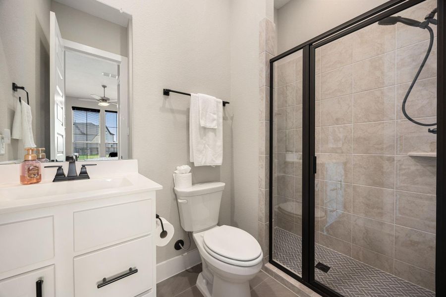 This private en suite bath in the first-floor guest suite features a sleek vanity with modern fixtures, a walk-in shower with stylish tile surround, and contemporary finishes throughout. A perfect blend of comfort and convenience, it provides guests with both privacy and elegance.