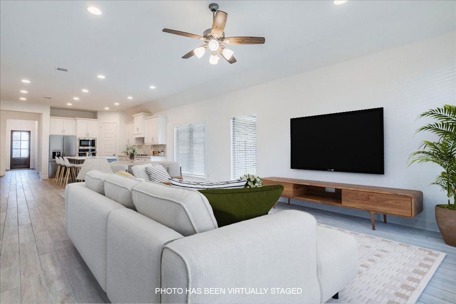 The spacious living area features recessed lighting, light-toned flooring, and a ceiling fan