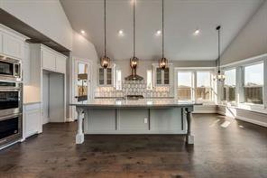 Kitchen featuring white cabinets, a kitchen bar, hanging light fixtures, and tasteful backsplash