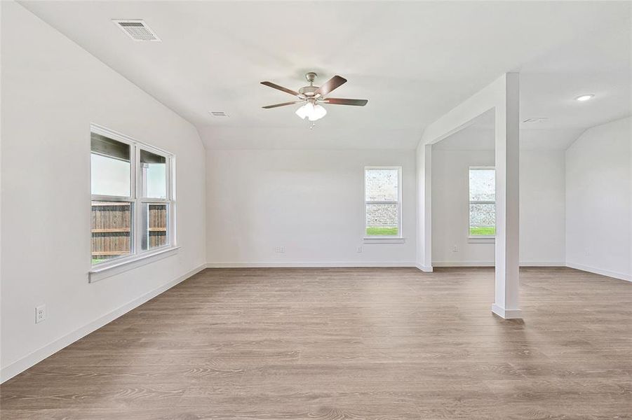 Empty room with ceiling fan, vaulted ceiling, and light hardwood / wood-style floors