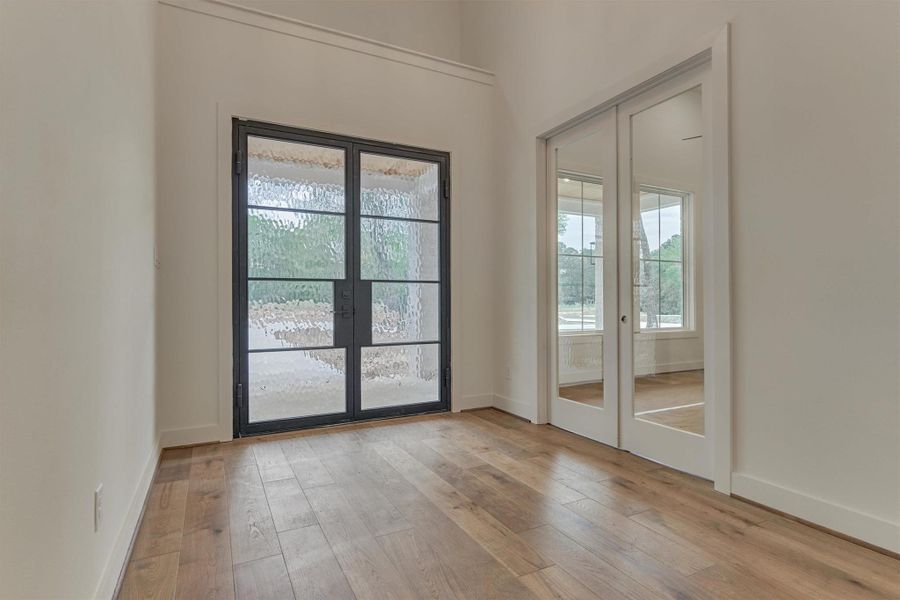 Light-filled entry with textured glass double doors and a stylish set of glass-paneled sliding doors leading into the private home office.