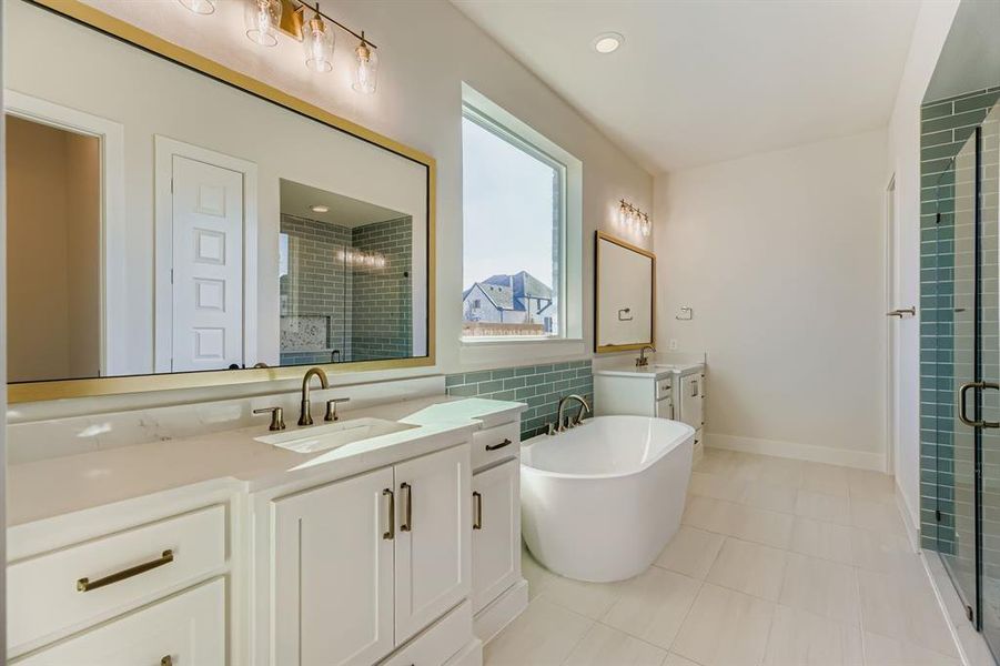 Bathroom featuring a soaking tub, two vanities, a stall shower, and light tile patterned floors