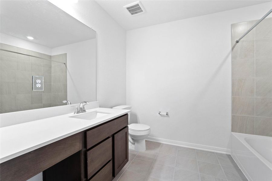 The secondary bathroom showcases tile flooring, a bath/shower combo with a Daltile tile surround, a vanity with knee space and a stunning light countertop, a mirror, sleek fixtures, and contemporary finishes throughout. The secondary bathroom showcases tile flooring, a bath/shower combo with a Daltile tile surround, a vanity with knee space and a stunning light countertop, a mirror, sleek fixtures, and contemporary finishes throughout.