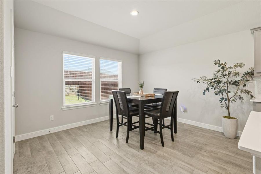 Dining area featuring wood-finish flooring, two windows with blinds, light gray walls, white baseboards, and a recessed ceiling light Dining area featuring wood-finish flooring, two windows with blinds, light gray walls, white baseboards, and a recessed ceiling light