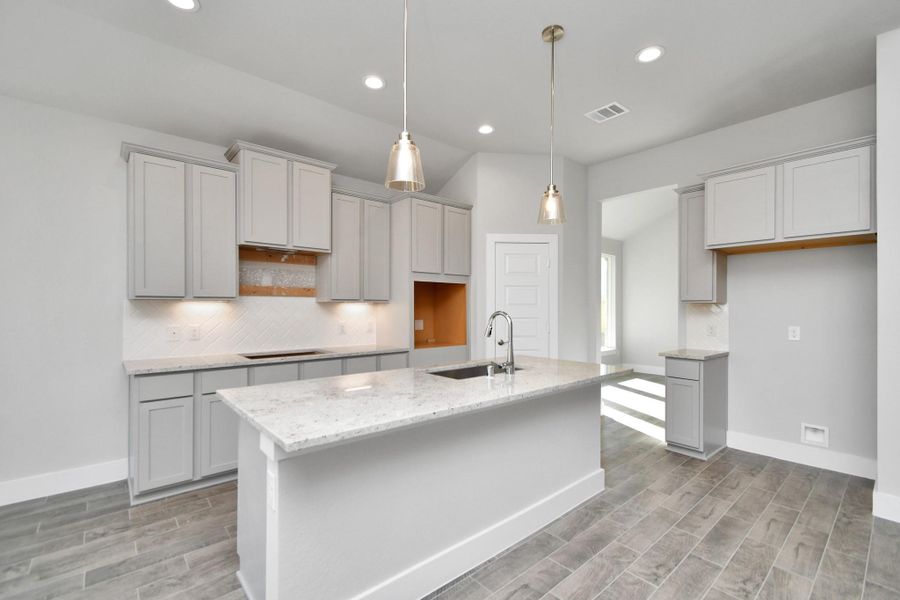 Discover another perspective of this stunning kitchen, generously appointed with an abundance of counter space. Sample photo of completed home with similar plan. As built color and selections will vary. Discover another perspective of this stunning kitchen, generously appointed with an abundance of counter space. Sample photo of completed home with similar plan. As built color and selections will vary.