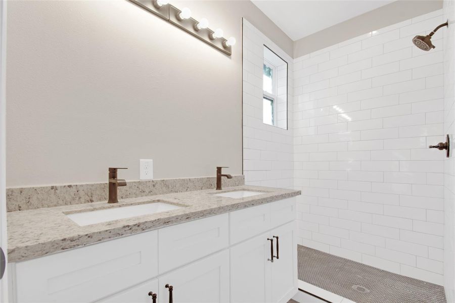 Full bathroom featuring double vanity and a shower stall