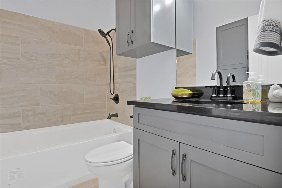 Spare bathroom with granite vanity, upscale fixture and hardware and an oversized shower/tub enclosure with body sprayer.