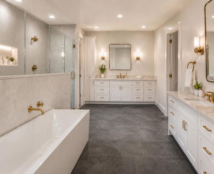 Polished stone tile floors anchor this master bath featuring dual vanities and a soaking tub.