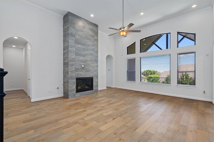 Spacious room featuring a floor-to-ceiling tiled fireplace, vaulted ceilings, and wood-finish flooring