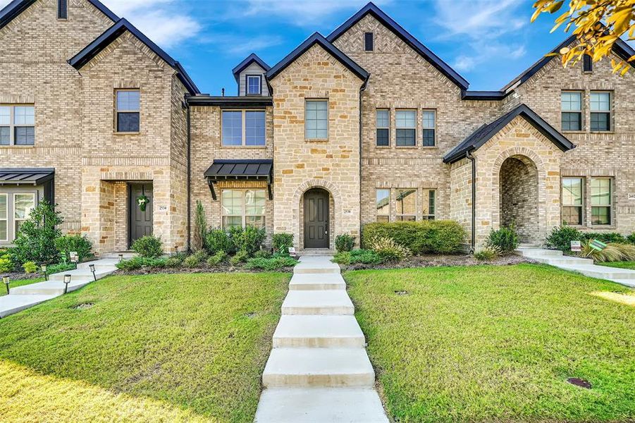 French country home with a front yard, brick siding, a standing seam roof, and a metal roof French country home with a front yard, brick siding, a standing seam roof, and a metal roof