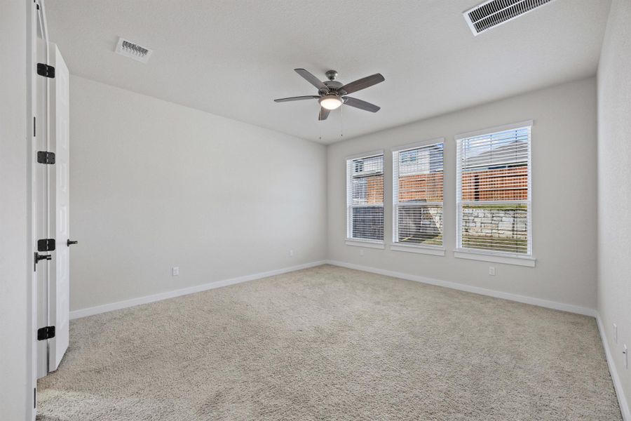 Primary bedroom featuring light carpet and a ceiling fan