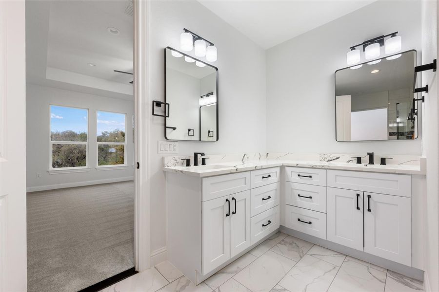 Bathroom featuring double vanity, light marble finish floors, and light colored carpet