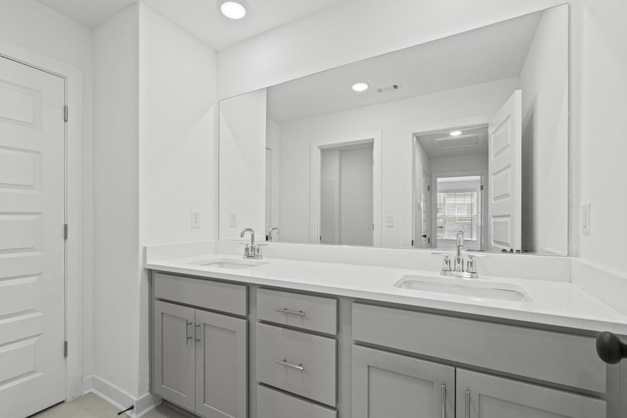 Dual vanity with light gray shaker cabinetry, integrated sinks, white countertops, and chrome fixtures