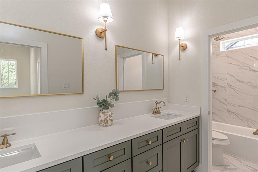 Dual vanity with dark cabinetry, white countertops, and brass hardware