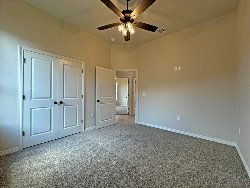 Unfurnished bedroom featuring light colored carpet, ceiling fan, and a closet