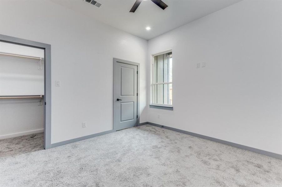 Unfurnished bedroom with ceiling fan, a closet, and light carpet