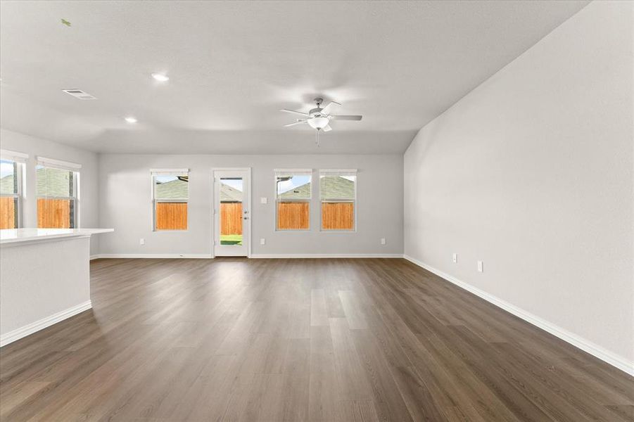 Unfurnished living room featuring ceiling fan, a healthy amount of sunlight, and dark hardwood / wood-style flooring