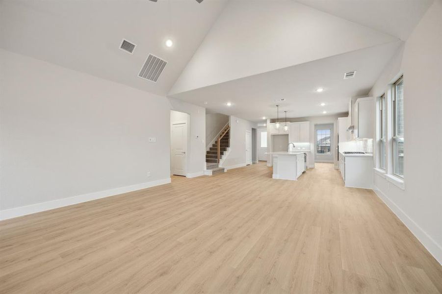 Unfurnished living room featuring high vaulted ceiling and light hardwood / wood-style floors