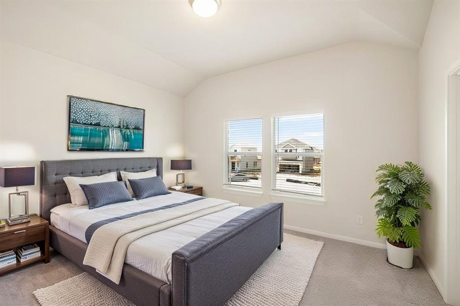 This serene bedroom is bathed in natural light from the large windows, creating a bright and welcoming space. Plush carpeting and a neutral color palette offer a cozy ambiance, perfect for restful nights and relaxing mornings.