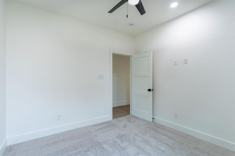 Empty room with light colored carpet and ceiling fan