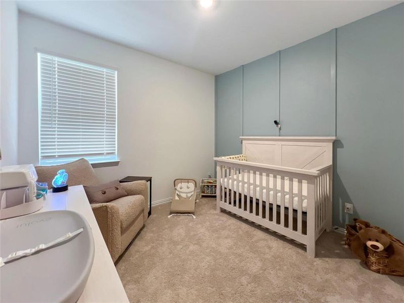 Bedroom featuring a crib and light colored carpet
