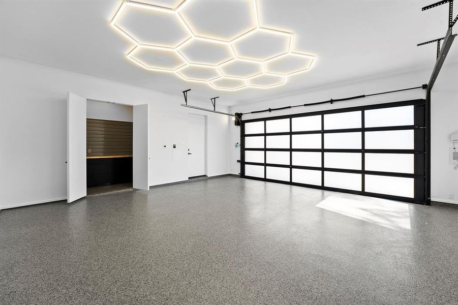 Spacious garage with hexagonal ceiling lighting and a glass-paneled roll-up door