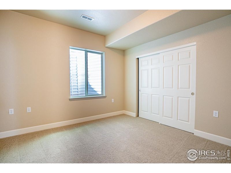 Basement bedroom with tall ceilings and full egress window ladder