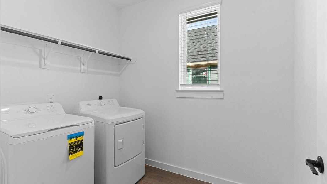 Spacious laundry room with washer and dryer connections, hanging rod, and vinyl wood flooring