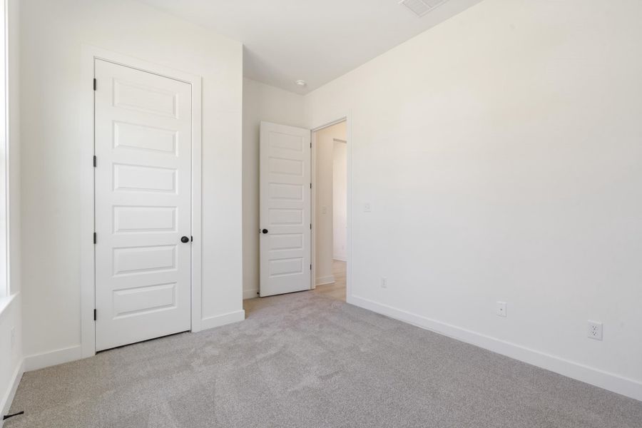 Neutral-toned carpeting, five-panel interior doors, and matte black door hardware Neutral-toned carpeting, five-panel interior doors, and matte black door hardware