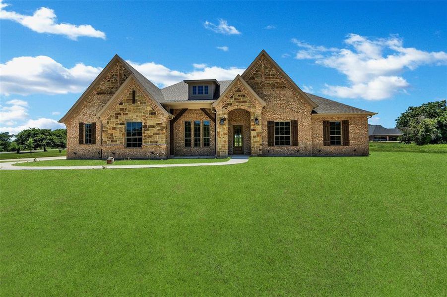 View of front of home with brick siding, a front lawn, and a shingled roof
