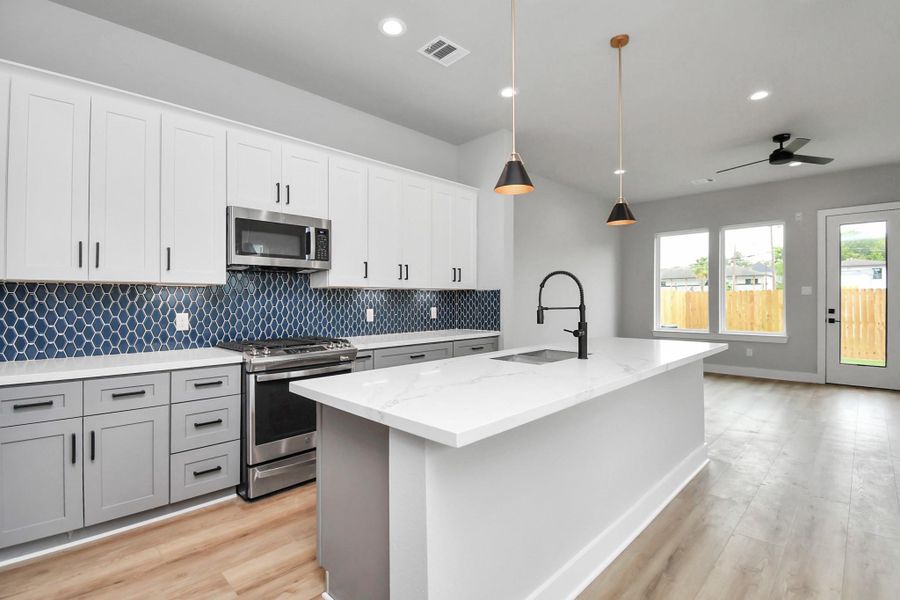 Modern kitchen featuring a large island, sleek finishes, and designer backsplash. Open layout connects seamlessly to the living area, ideal for entertaining.