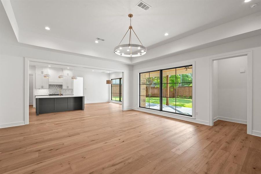Unfurnished living room featuring a tray ceiling, recessed lighting, and light wood-type flooring Unfurnished living room featuring a tray ceiling, recessed lighting, and light wood-type flooring
