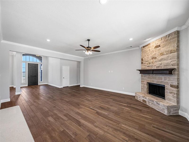 Prior listing photo. Property remains accurate - Unfurnished living room with a ceiling fan, crown molding, dark wood-style flooring, a fireplace, and recessed lighting