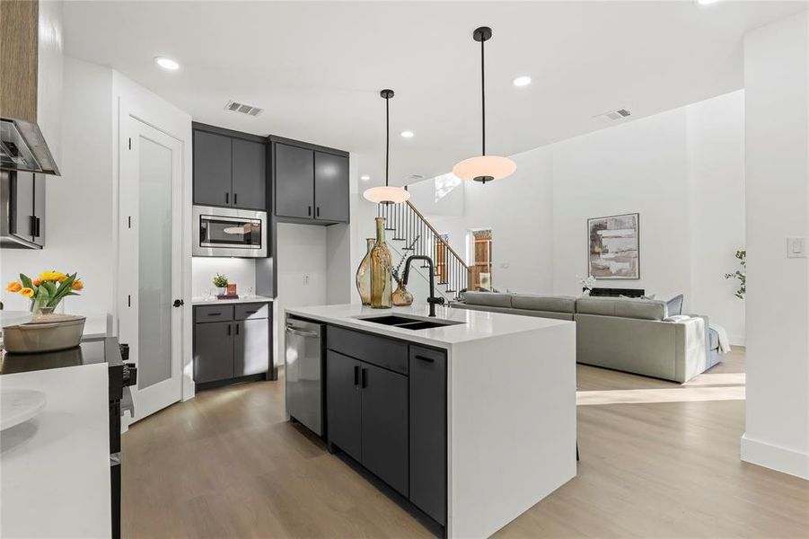 Kitchen featuring a kitchen island with sink, pendant lighting, light wood finished floors, open floor plan, and recessed lighting