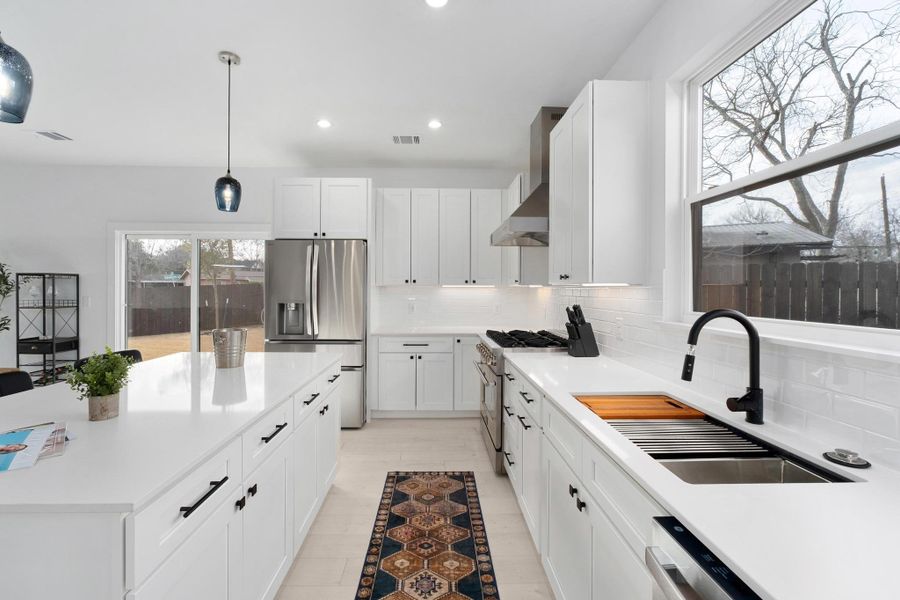 Kitchen featuring white cabinets, stainless steel appliances, hanging light fixtures, backsplash, and a center island