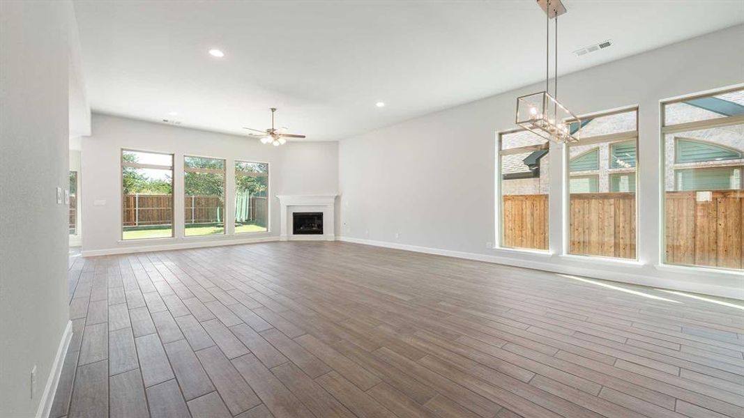 Unfurnished living room with wood-type flooring and ceiling fan with notable chandelier